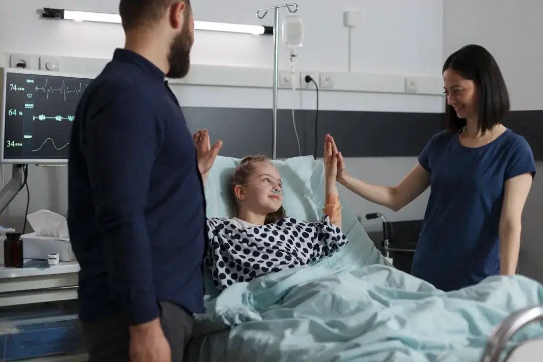 Jeune fille hospitalisée, entourée de ses parents, illustrant l’accompagnement des familles confrontées au cancer, à une maladie grave ou au handicap d’un enfant.