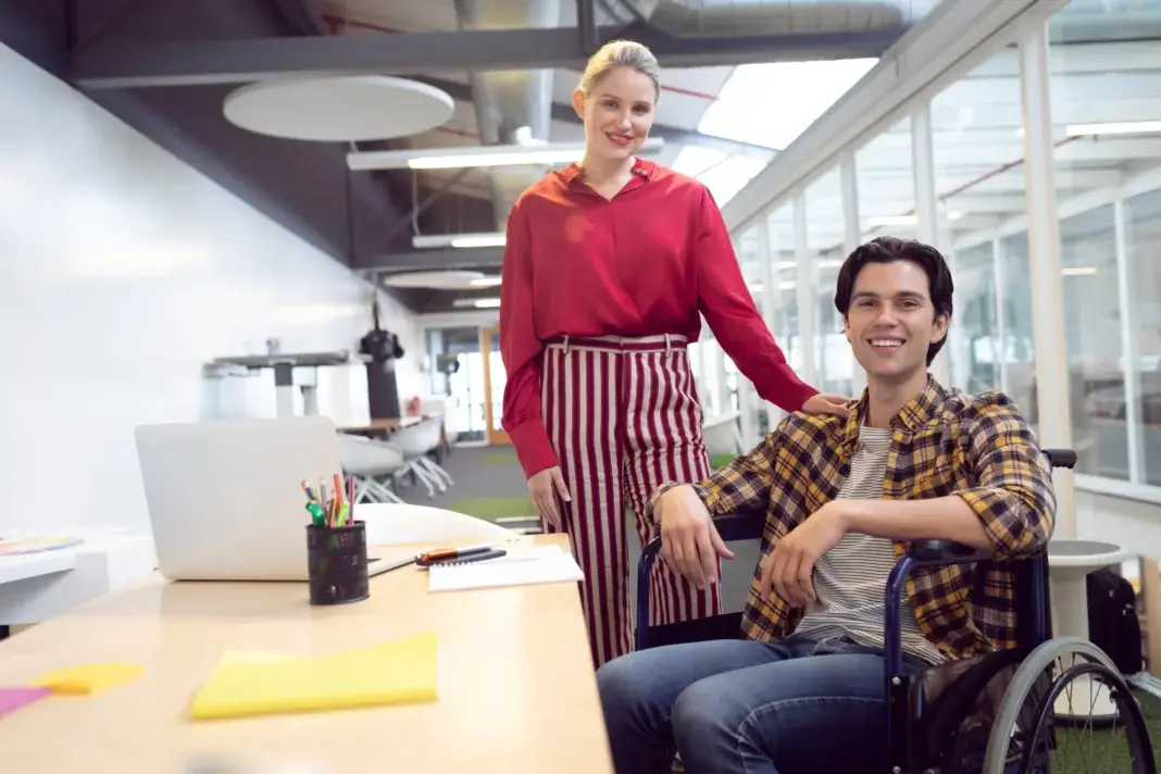 Deux professionnels dans un espace de travail, dont une personne en fauteuil roulant, illustrant l’accompagnement vers un environnement professionnel adapté dans le cadre du nouveau parcours d’orientation en ESAT.